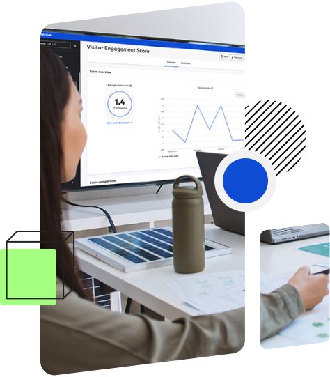 A person is sitting at a desk looking at a monitor displaying a 'Visitor Engagement Score' screen with graphs and data.