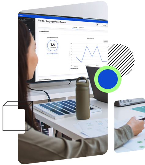 A person is sitting at a desk looking at a monitor displaying a 'Visitor Engagement Score' screen with graphs and data.