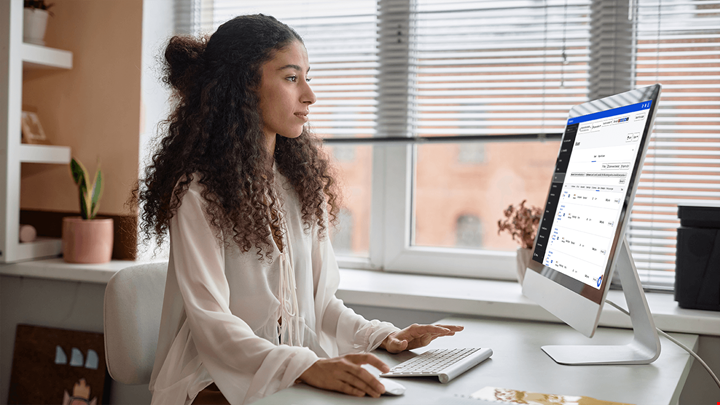 Woman sitting at a computer looking at the Siteimprove platform dashboard.